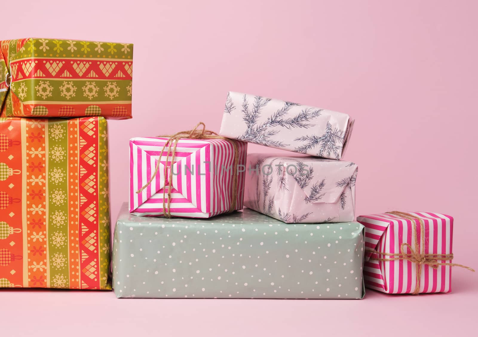 stack of colored paper wrapped gift boxes. great design for any purposes. pink background 
