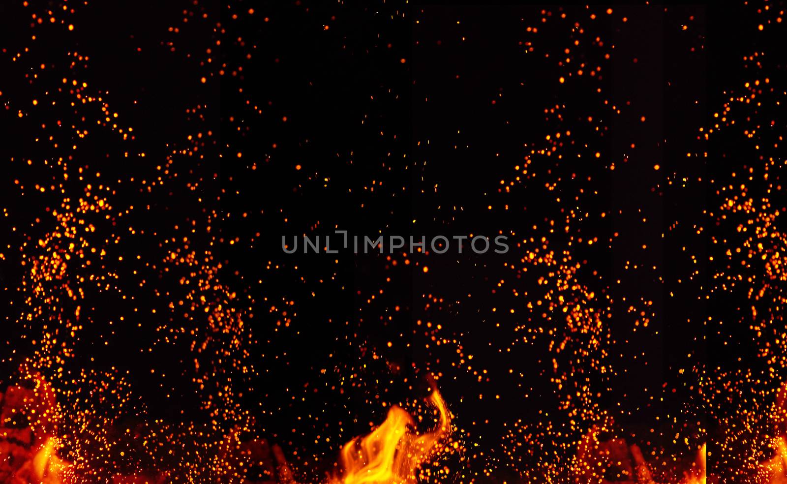 large burning bonfire with flame and orange sparks that fly in different directions on a black background, full frame