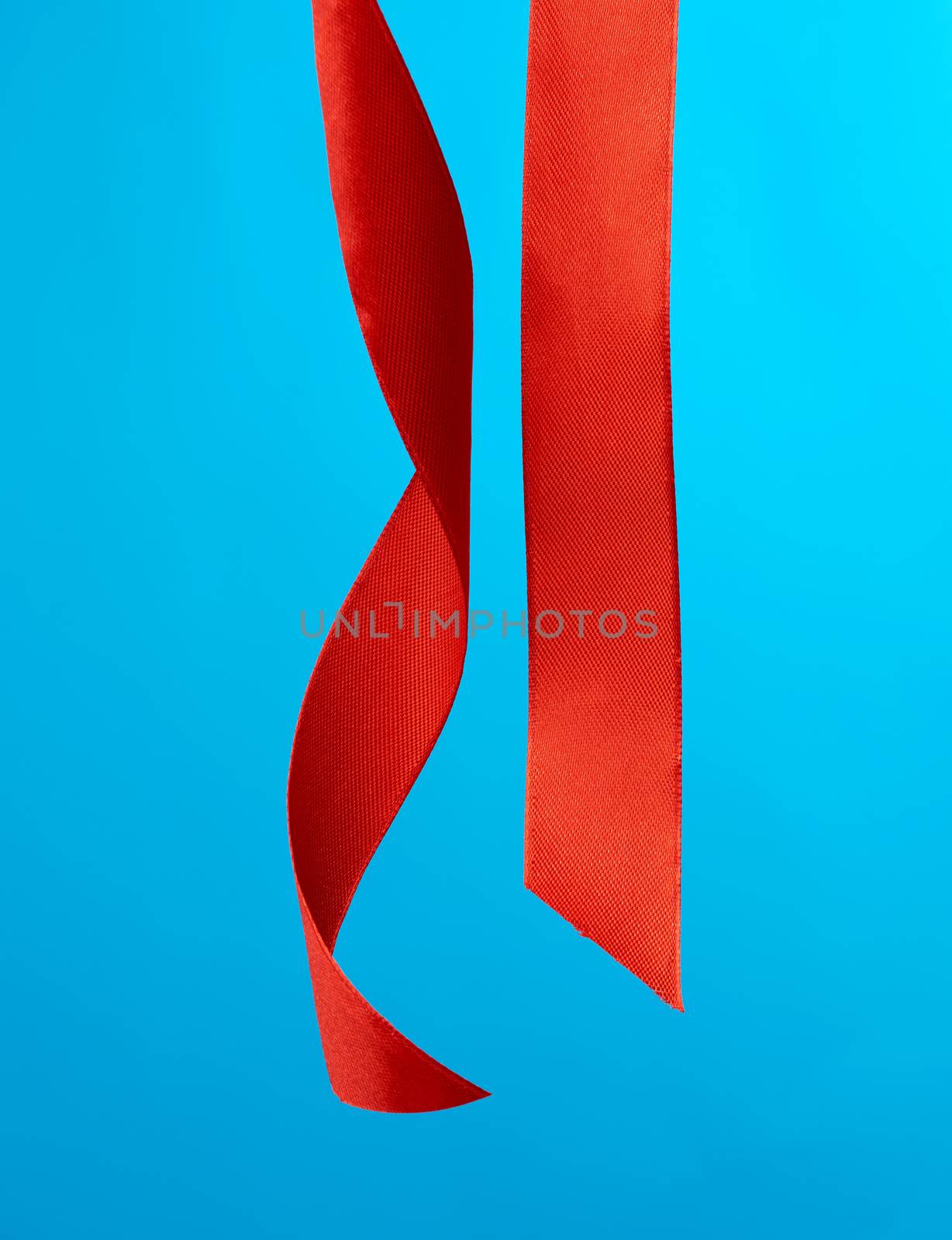 different ends of red silk ribbon on a blue background, close up