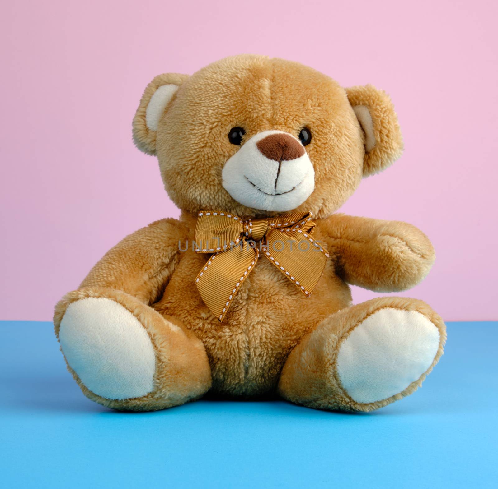 cute little brown teddy bear, toy is sitting on a blue background, close up