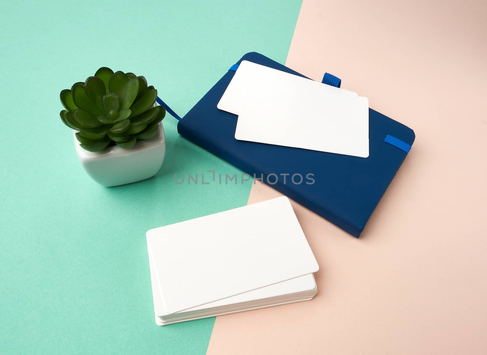 stack of rectangular white blank business cards and blue notebook on a green beige background, backdrop for the designer