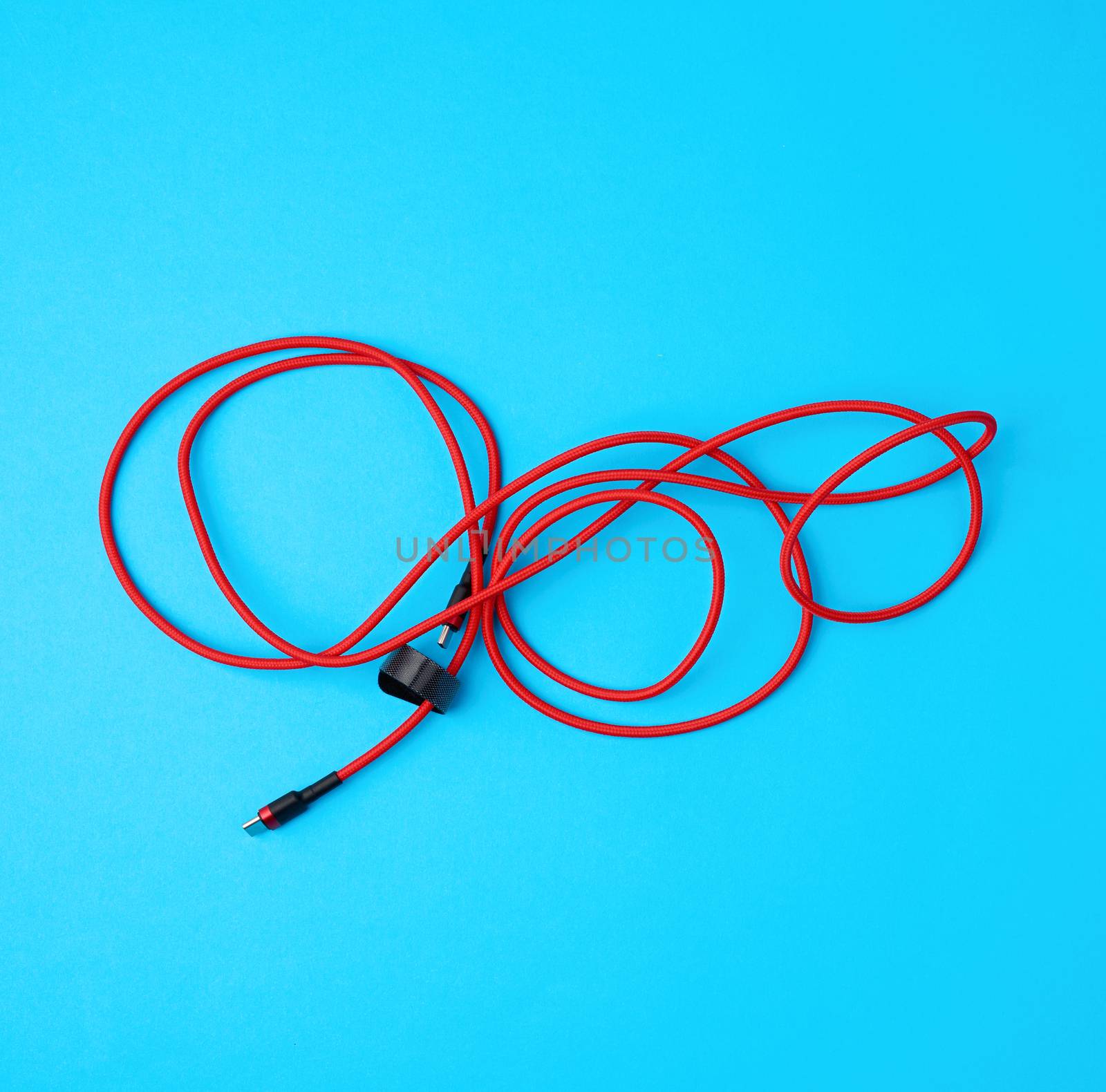 twisted cable for charging mobile devices in a red textile wrapper on a blue background