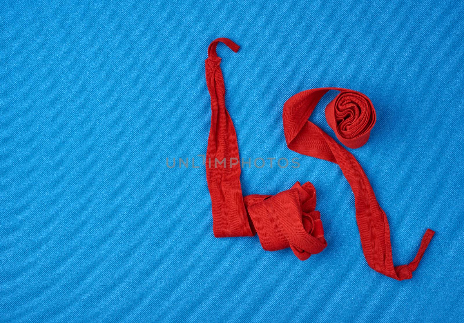 pair of textile red bandages for winding hands to athletes before sports training on a blue background, top view