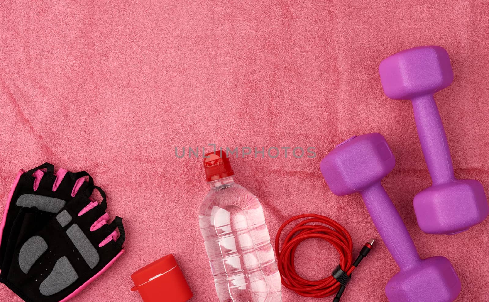 pair of purple plastic dumbbells, headphones,  and pink terry towel, top view, training equipment
