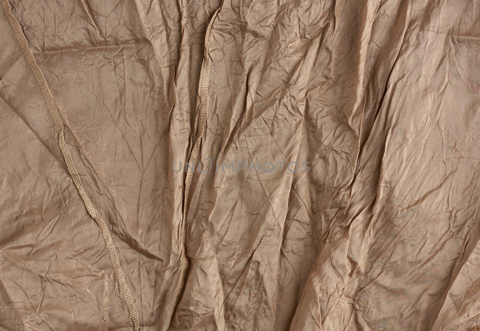 texture of crumpled brown synthetic fabric with seams for sewing clothes, full frame
