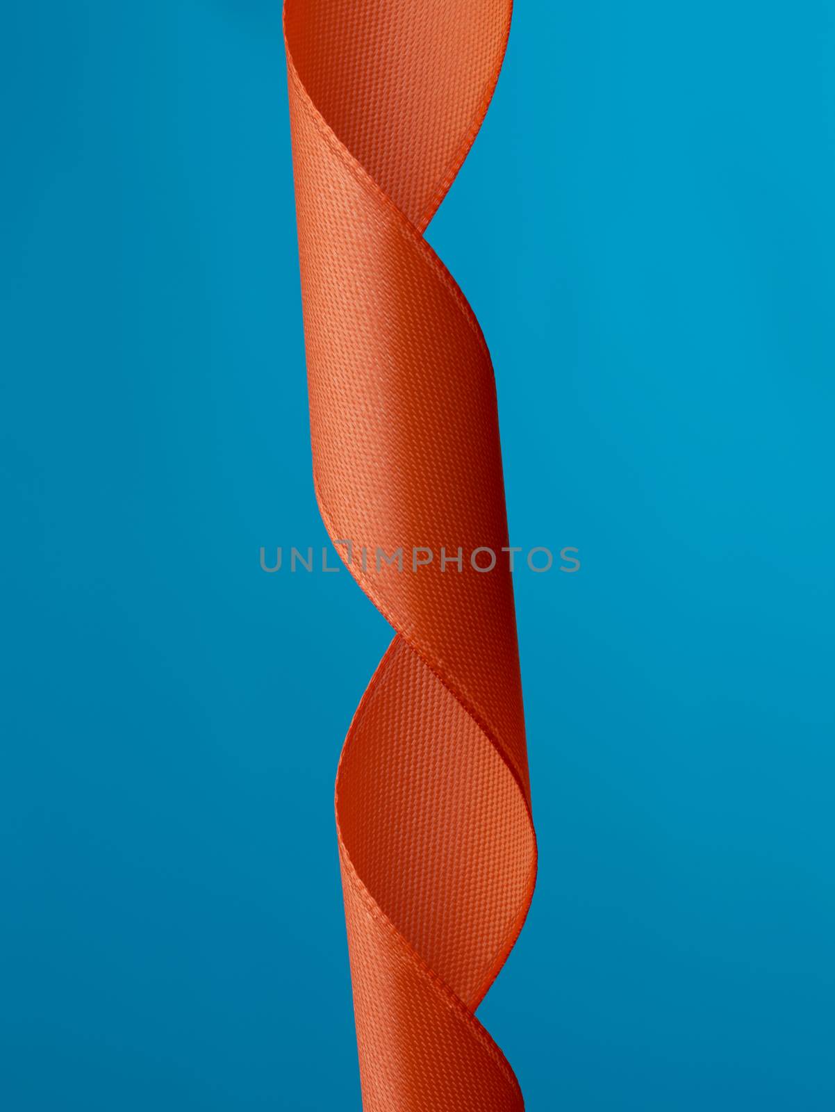 twisted silk red ribbon on a blue background, close up