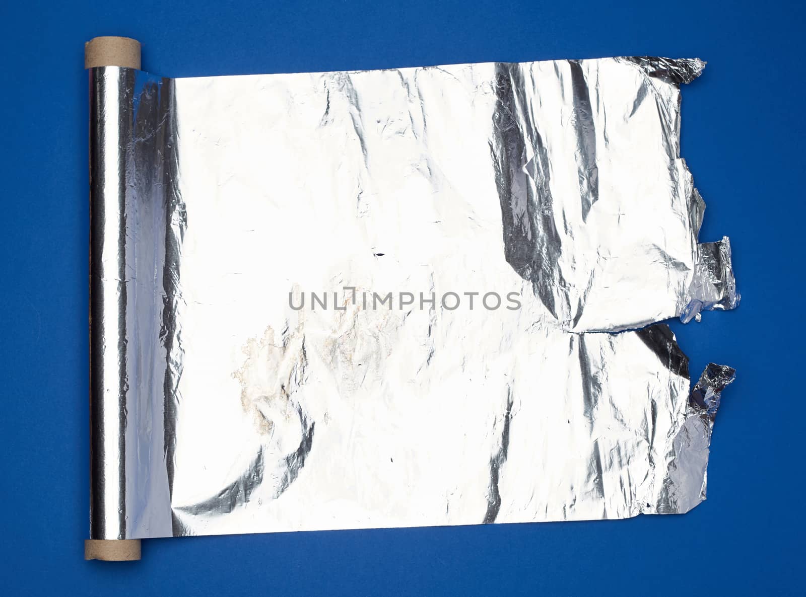 roll of gray foil for baking and packaging food on a dark blue background, torn edge