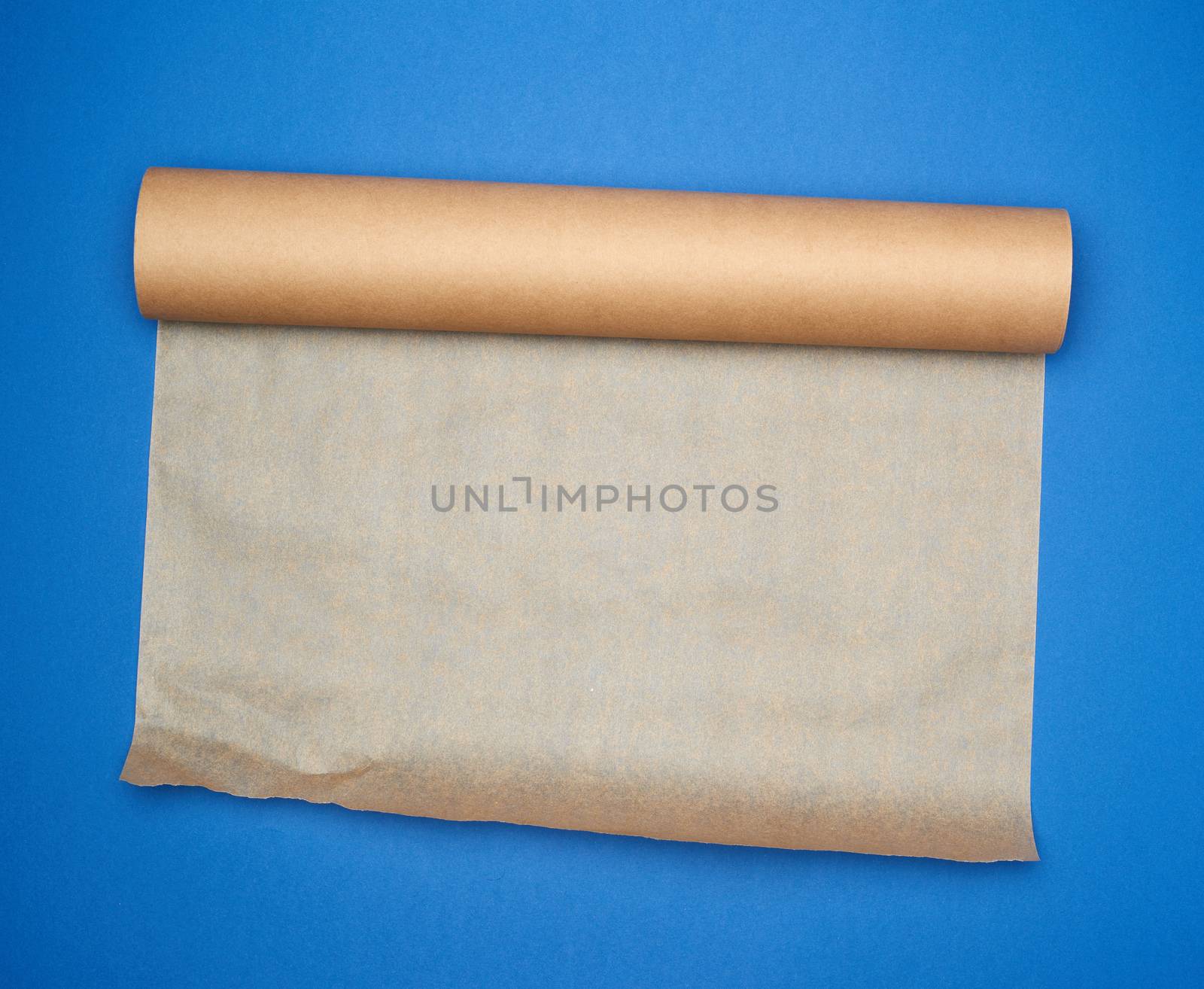 roll of brown parchment paper on a blue background, copy space, top view
