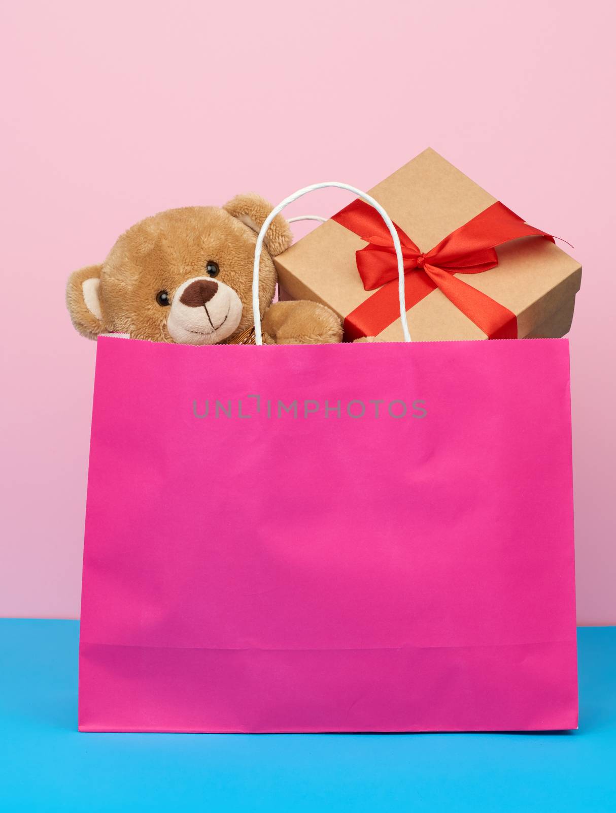 pink paper bag with a gift and a teddy bear, concept of shopping by ndanko
