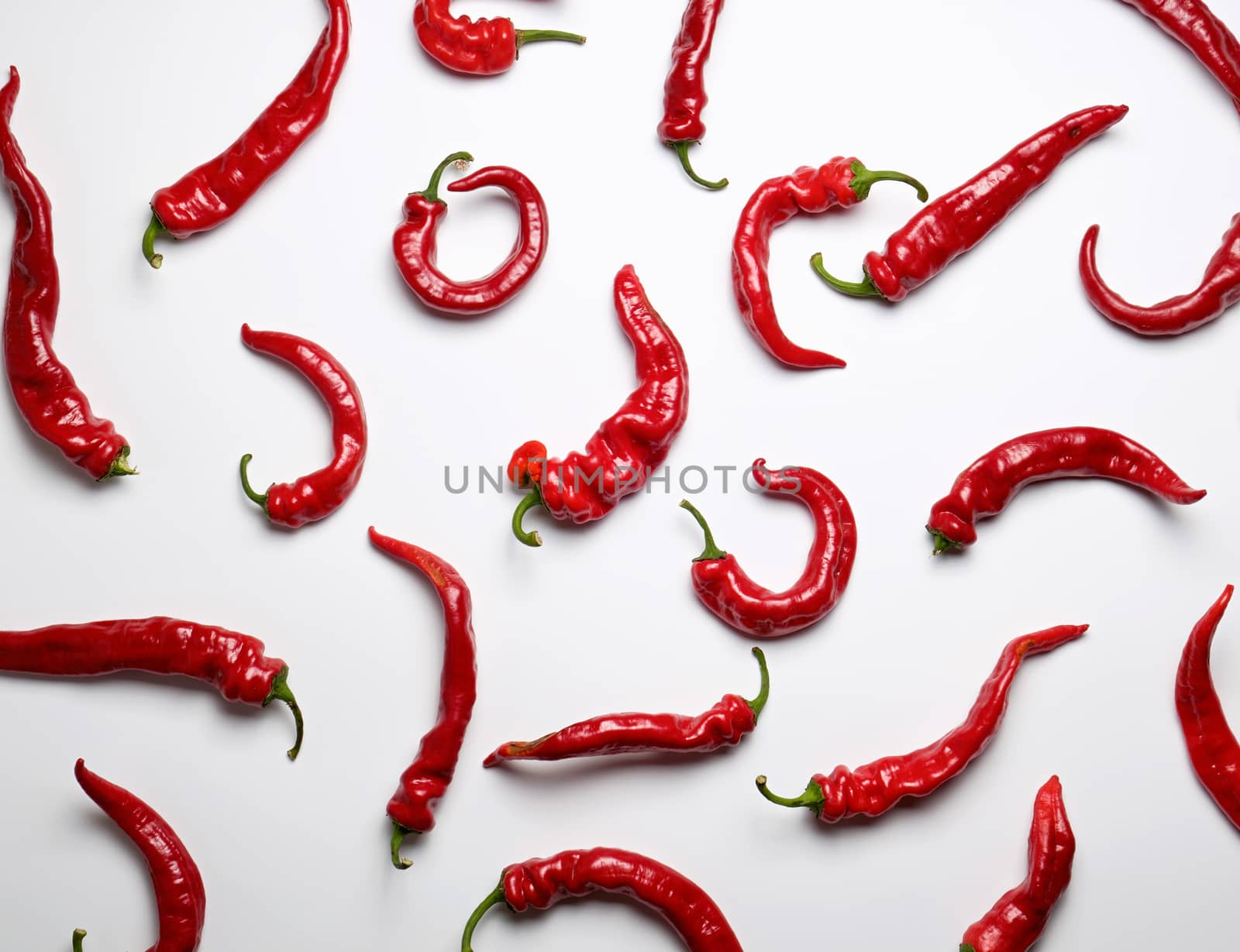 whole ripe red hot pepper scattered on a white background, fragrant spice for cooking, full frame