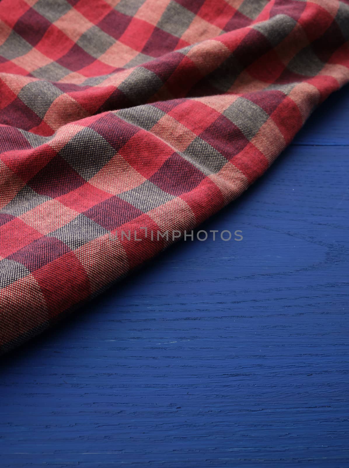 red checkered fabric on a blue wooden background by ndanko