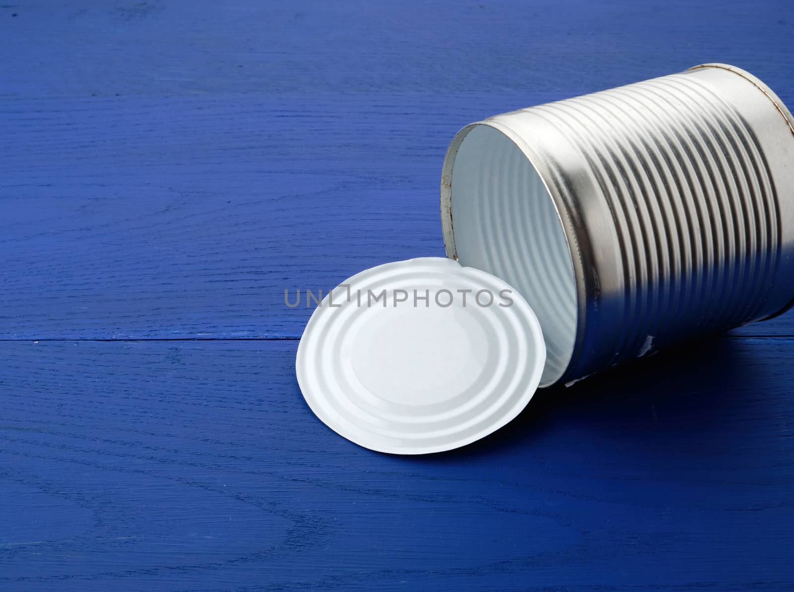open large metal tin can on a blue wooden background from parallel boards, top view