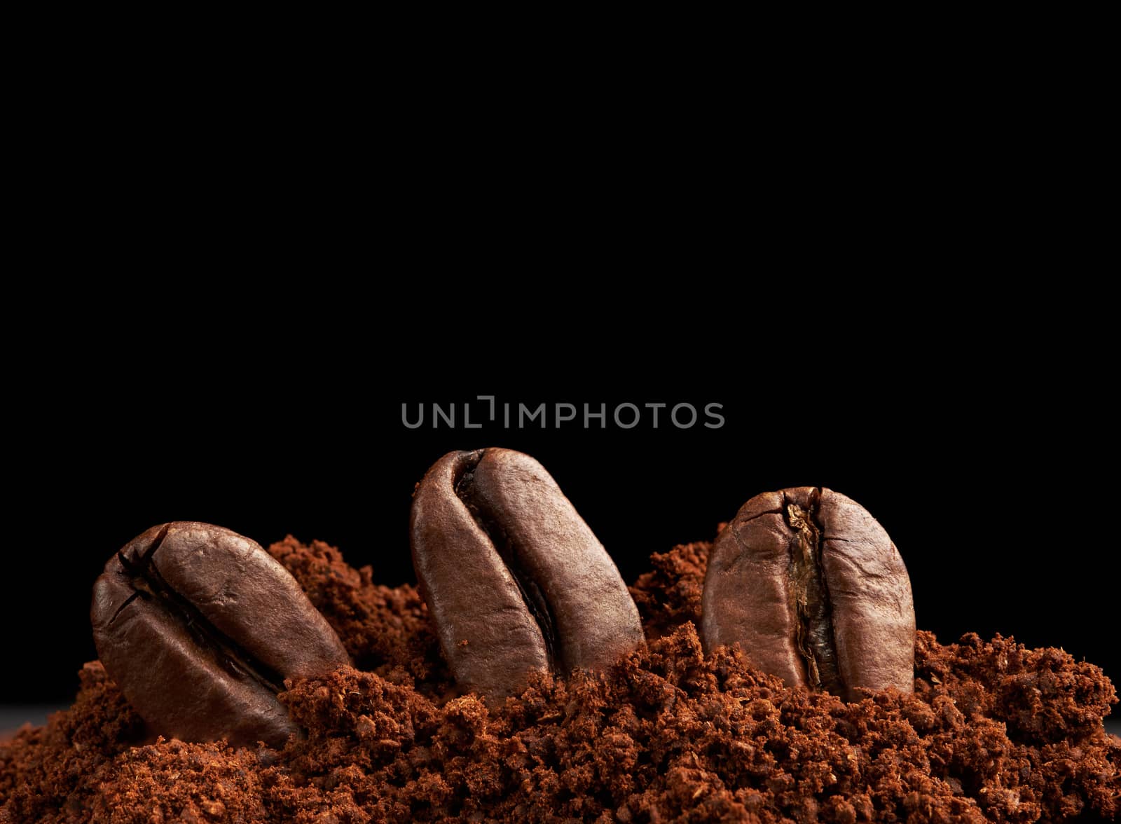 pile of ground roasted coffee arabica and whole grains on a black background, ingredient for a fragrant drink