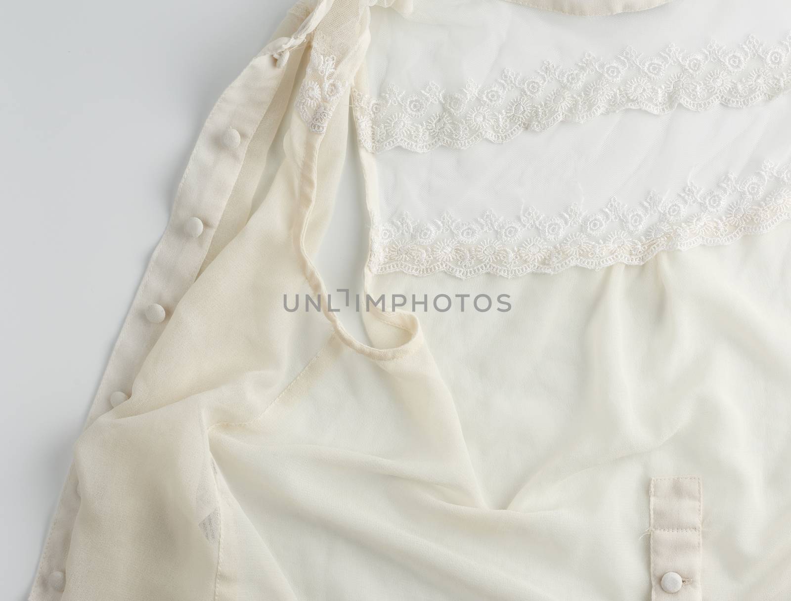fragment of a silk beige blouse with lace and buttons, close up