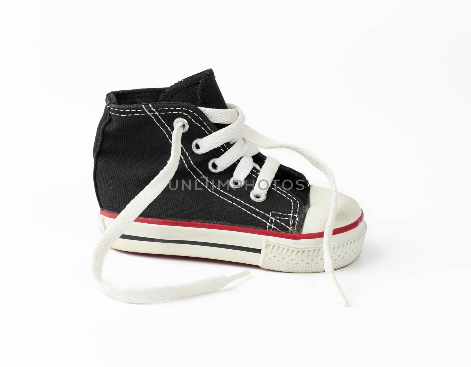 black textile children's sneaker with white untied shoelaces on a white background, shoes stand sideways