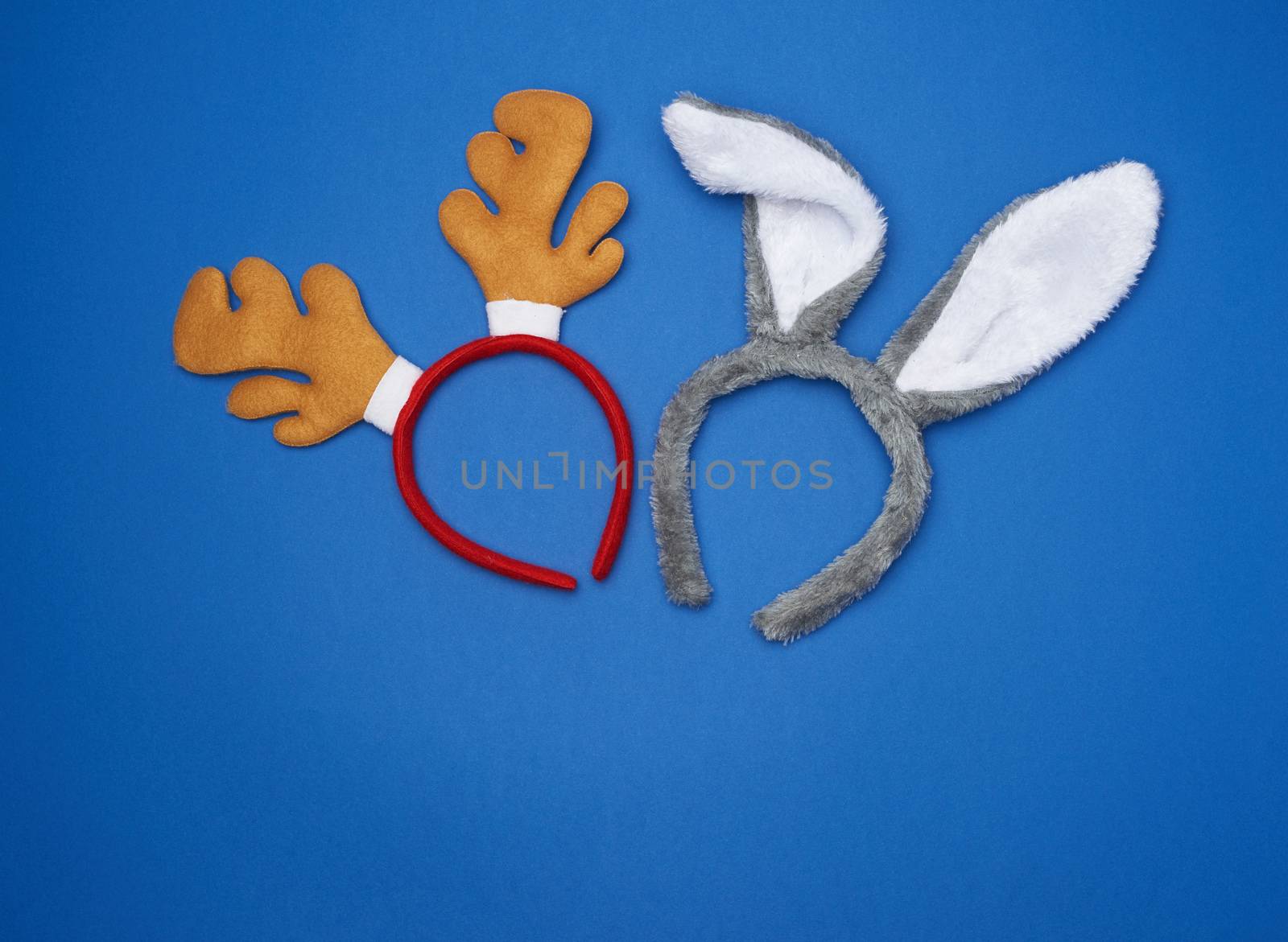 carnival masks of fur, hoop with rabbit and horned deer ears on a blue background, top view