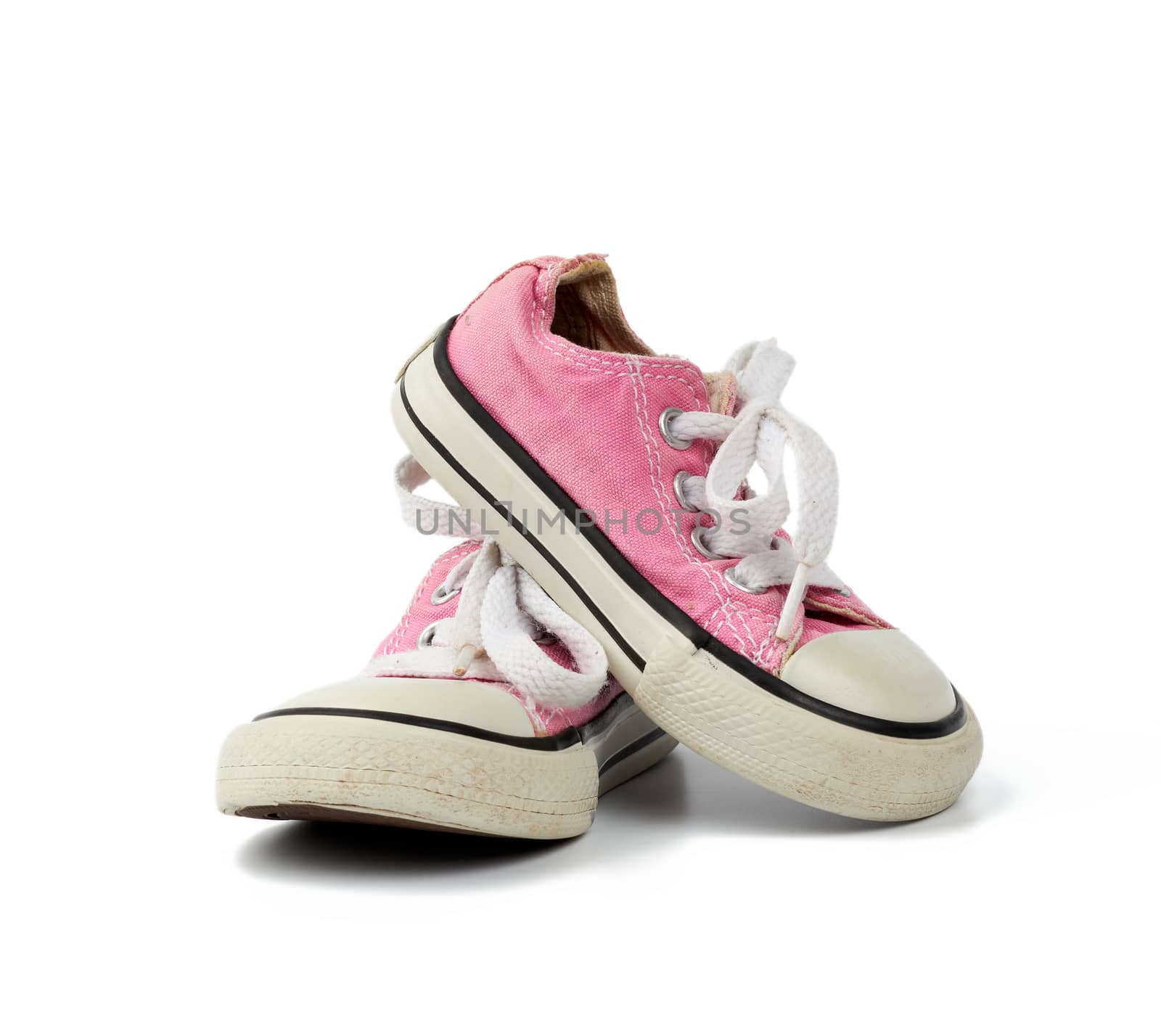 pair of pink children's textile sneakers with white laces isolated on a white background, old shoes