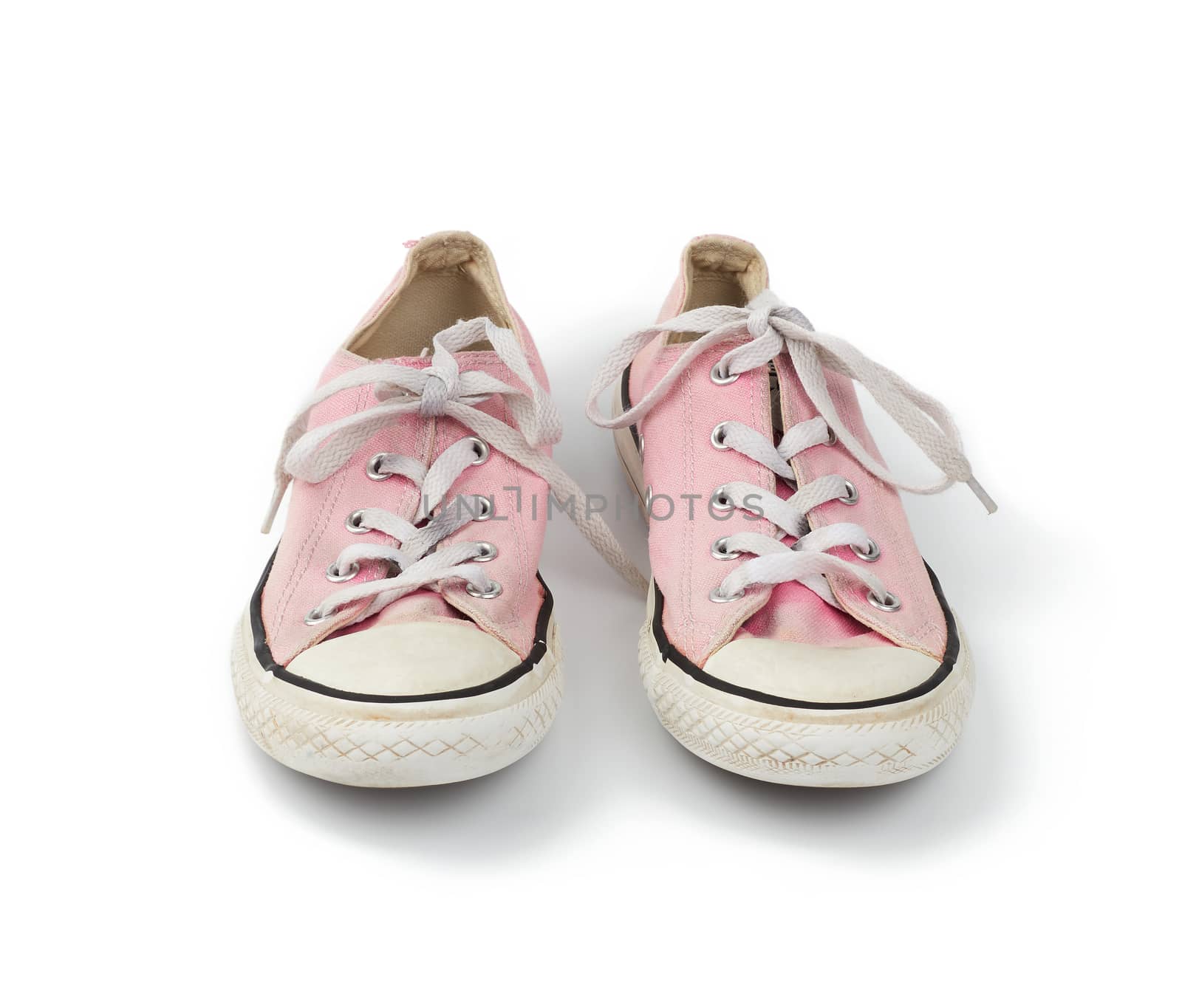 pair of light pink worn textile sneakers with laces isolated on a white background, front view