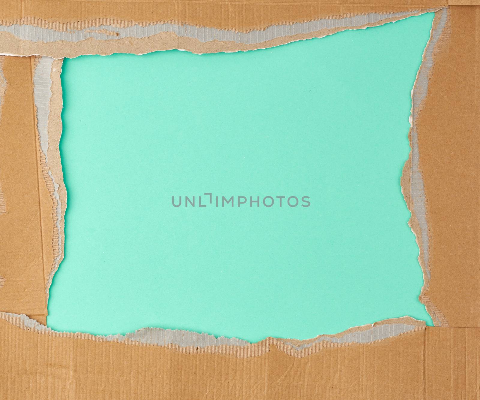 torn edges of corrugated brown cardboard paper on a green background. Ripped paper texture