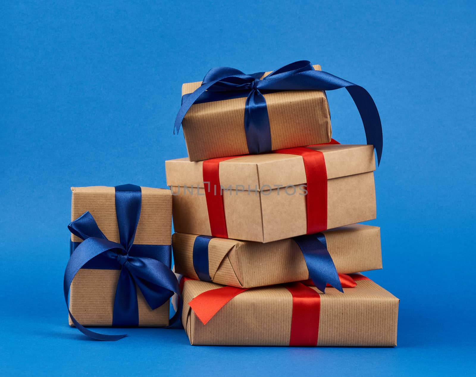 rectangle box wrapped in brown kraft paper and tied with a silk blue and red ribbon, gift on a dark blue background