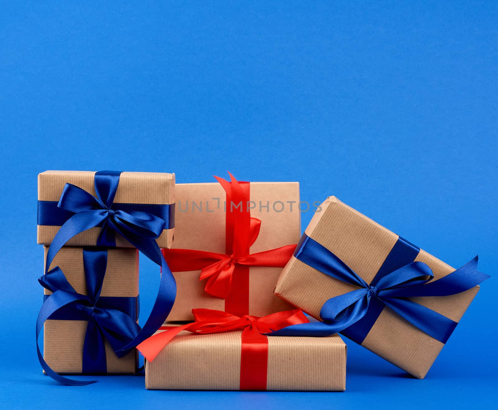 rectangle box wrapped in brown kraft paper and tied with a silk blue and red ribbon, gift on a dark blue background, holiday backdrop 