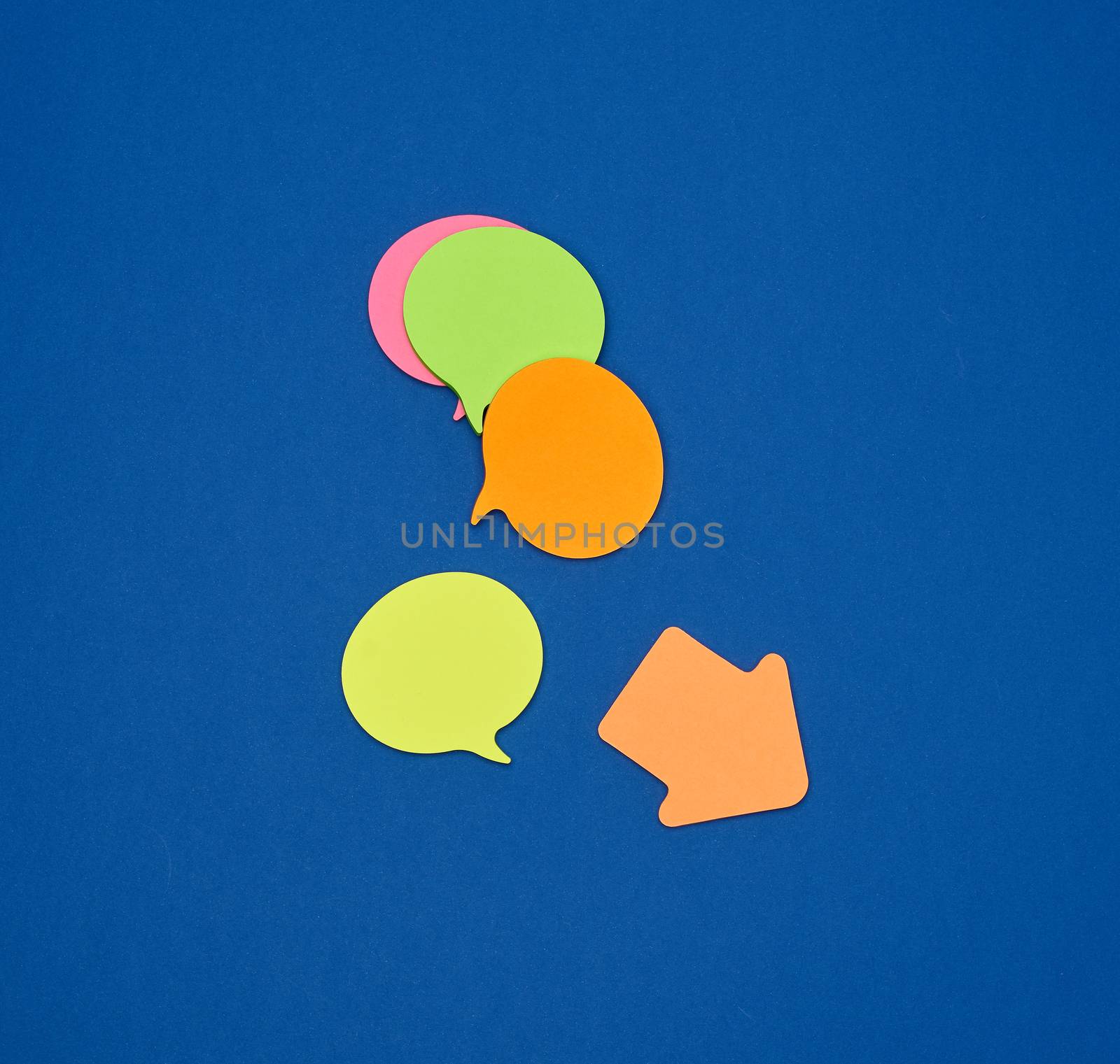 multicolored empty paper stickers in the form of clouds on a blue background, copy space