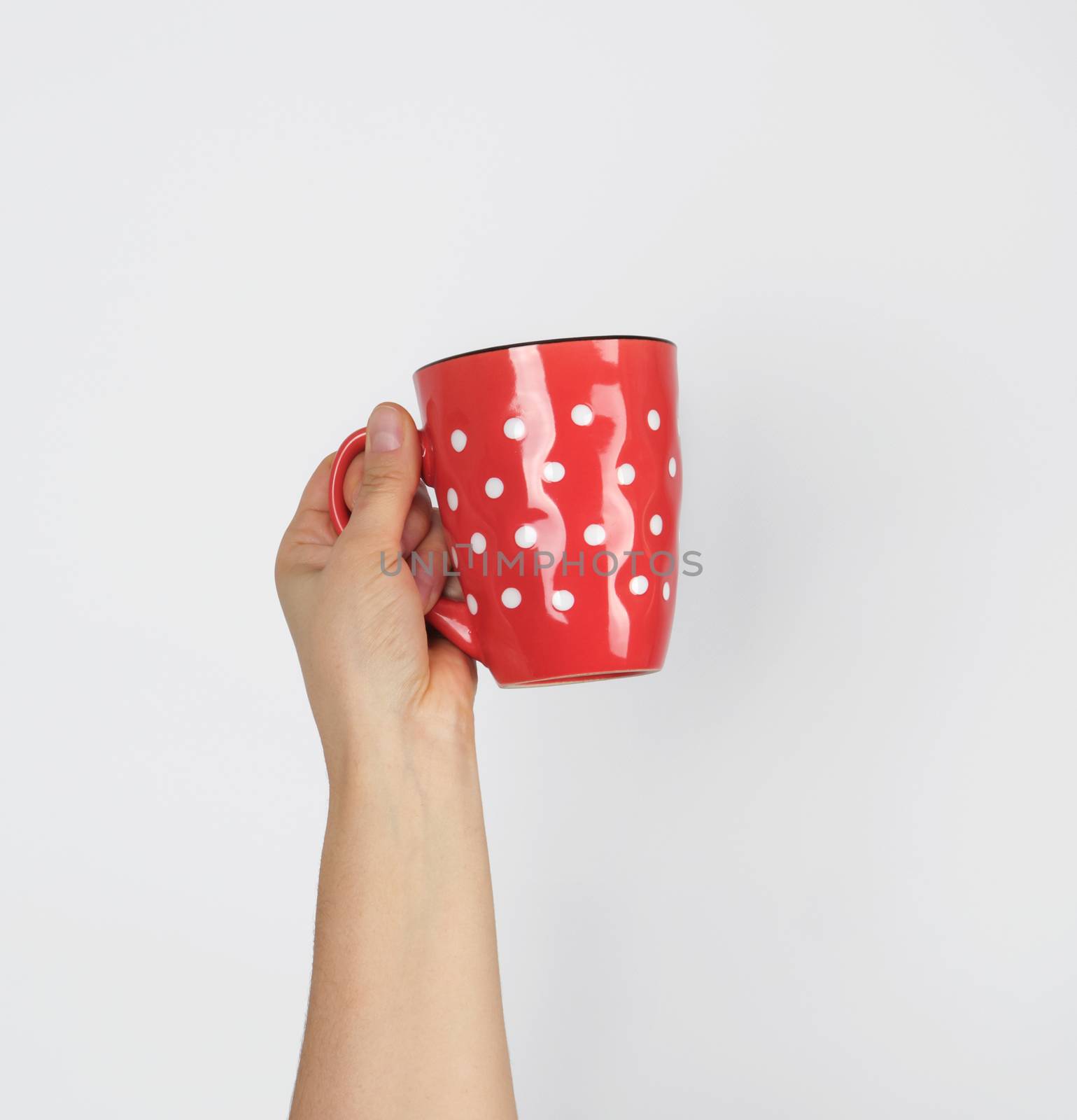 red ceramic cup in a female hand on a white background by ndanko
