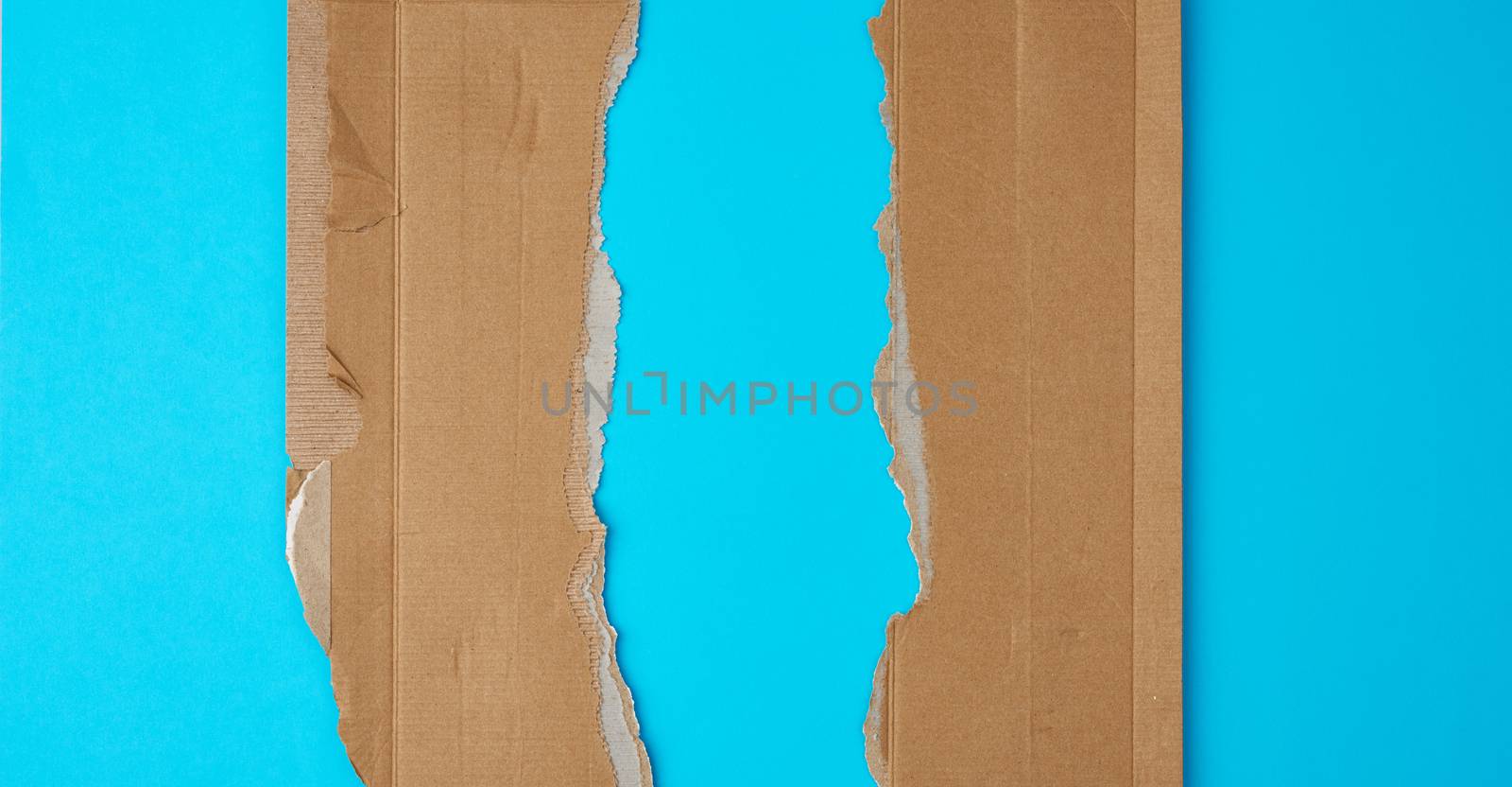 torn edges of corrugated cardboard paper on a light blue background, abstract backdrop template