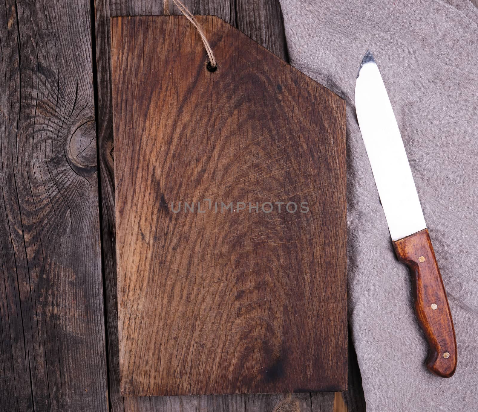 very old empty wooden rectangular cutting board and knife, top view, gray wooden background 