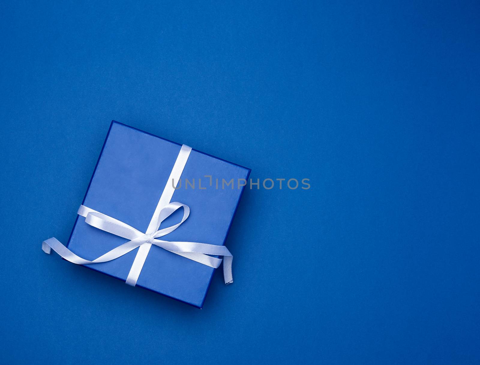 blue square box with a gift with a bow on a blue classic background, top view, empty place for an inscription