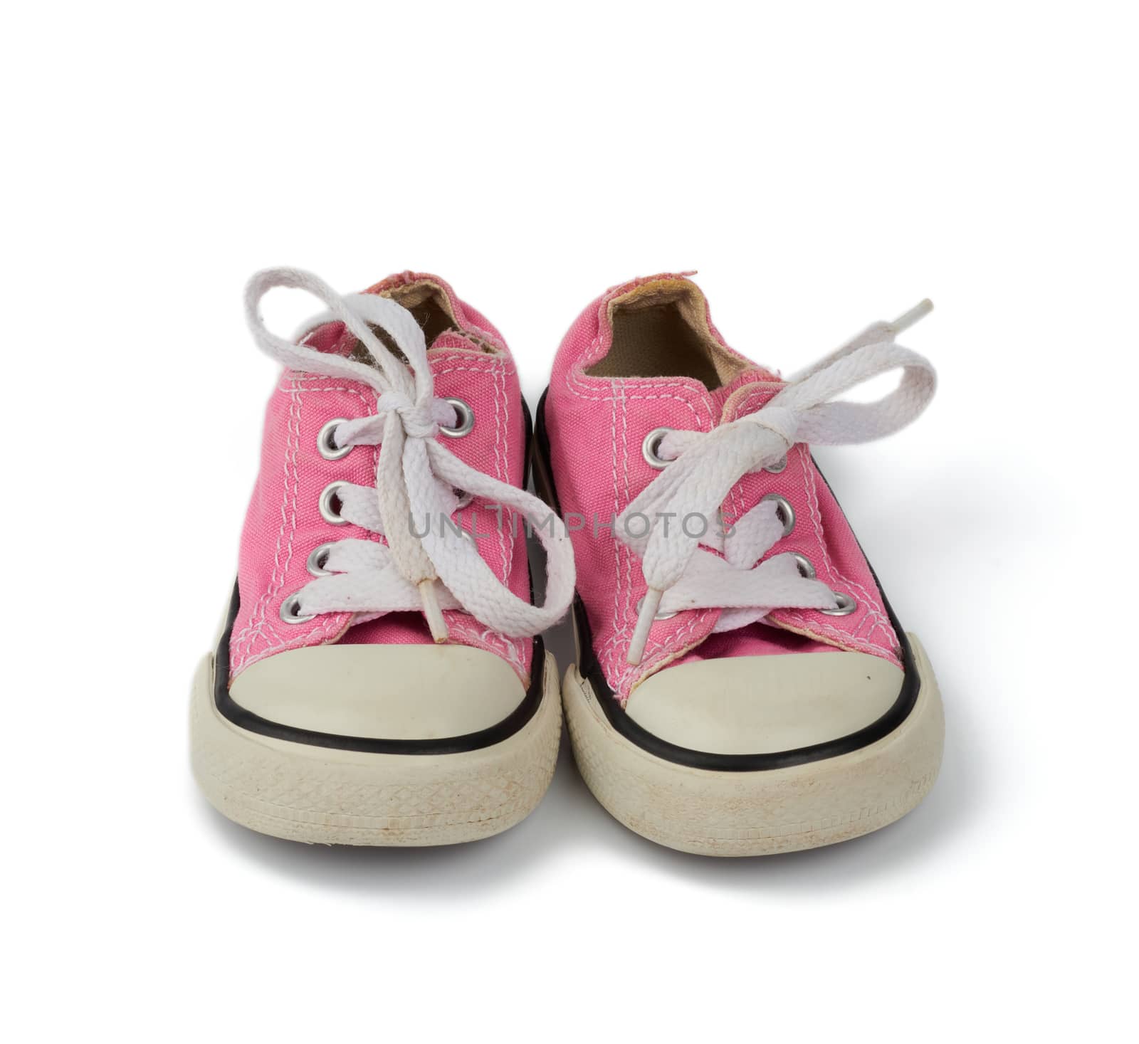 pair of pink children's textile sneakers with white laces isolated on a white background, old shoes