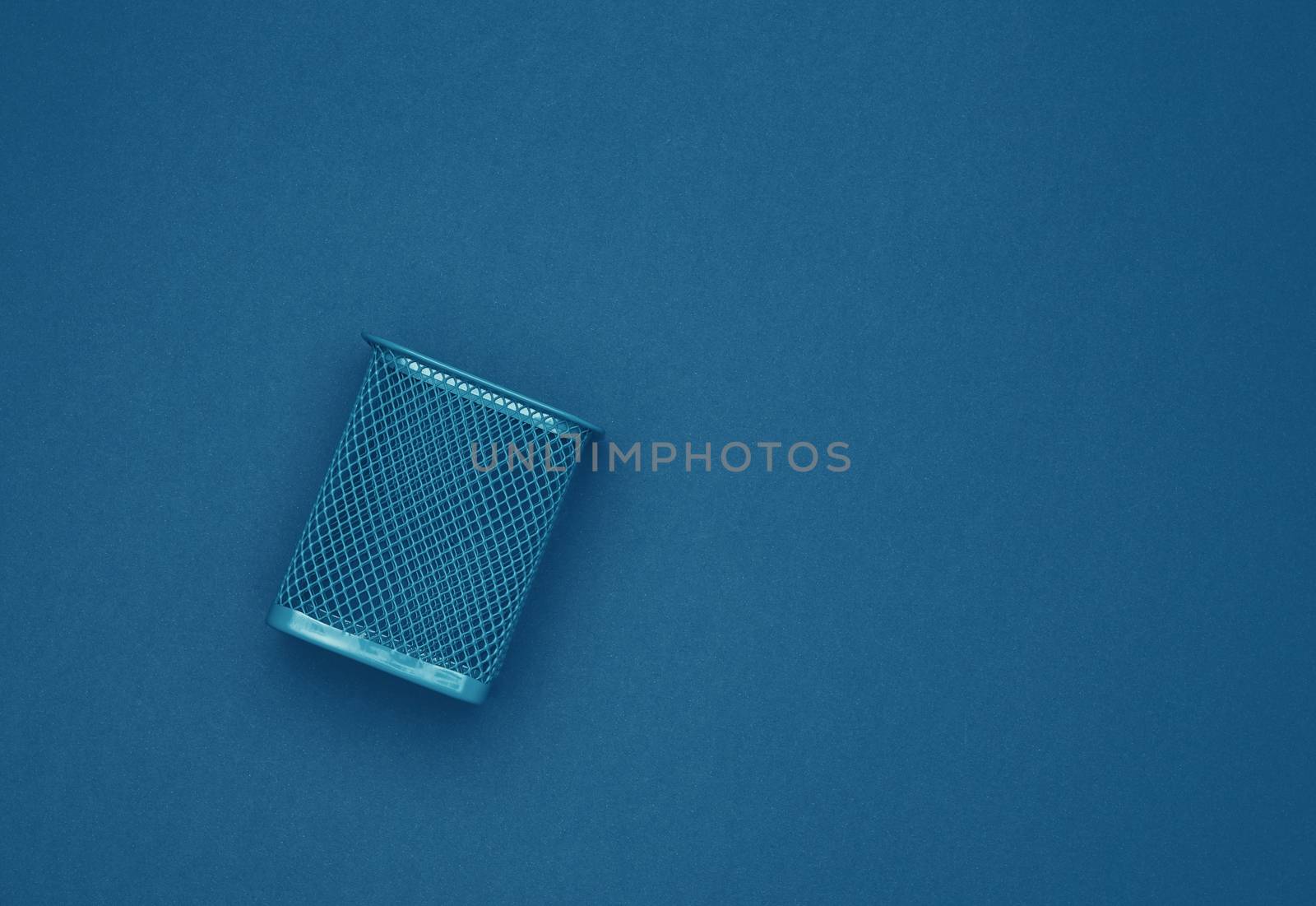 empty blue metal bin for paper, dark blue background, business concept