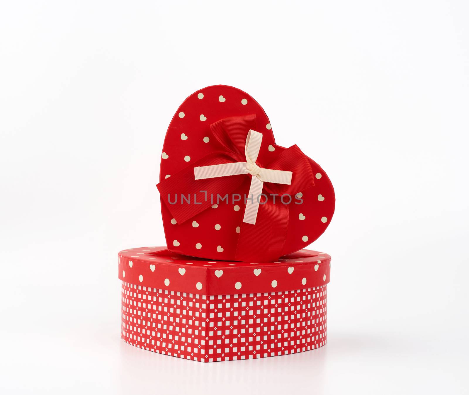 red heart-shaped cardboard box with bow on white background, holiday gift wrapping
