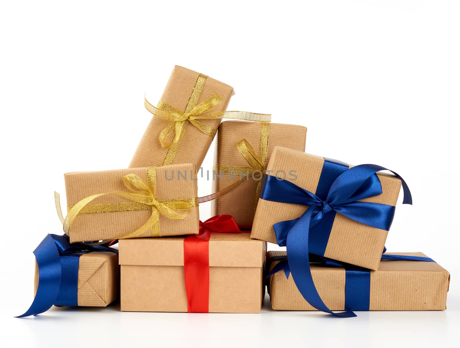 big stack of gifts wrapped in brown kraft paper and tied with silk blue and red ribbon, boxes isolated on white background, element for designer