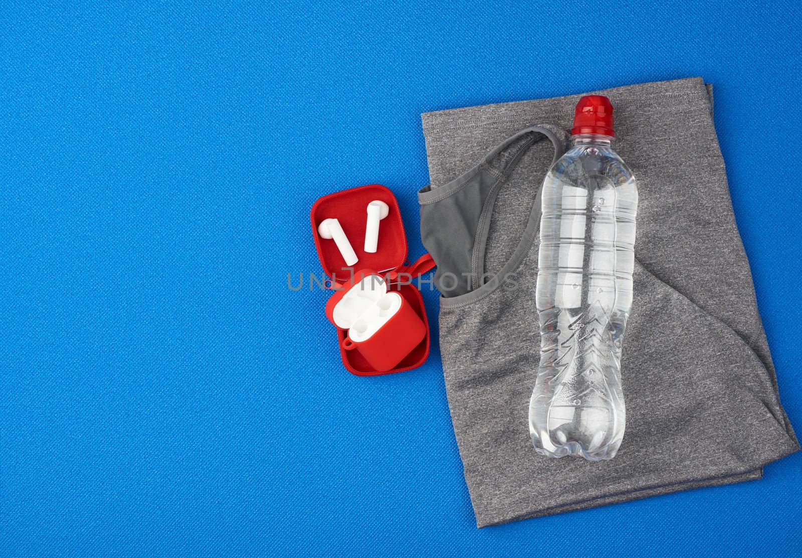 folded gray sports female T-shirt and water bottle on a blue background, set for sports and yoga