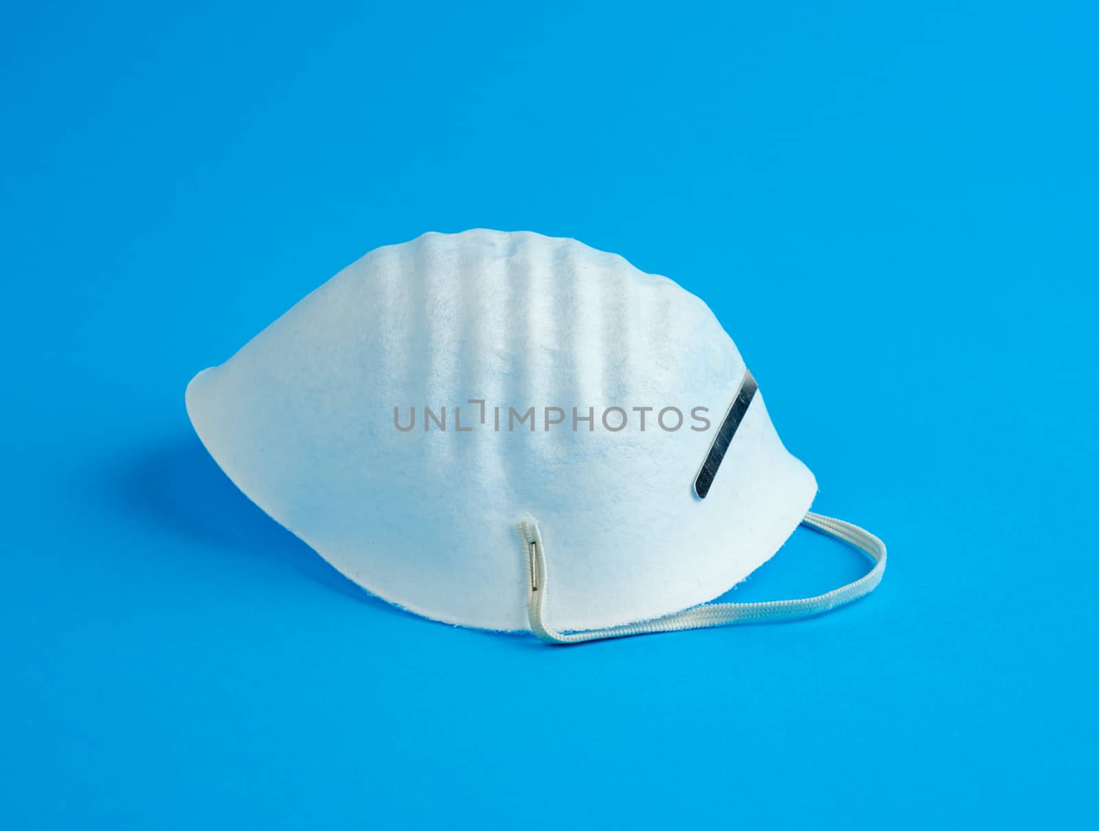 masks made of non-woven material with white rubber bands on a blue background, protective accessory for the respiratory tract from the virus, top view