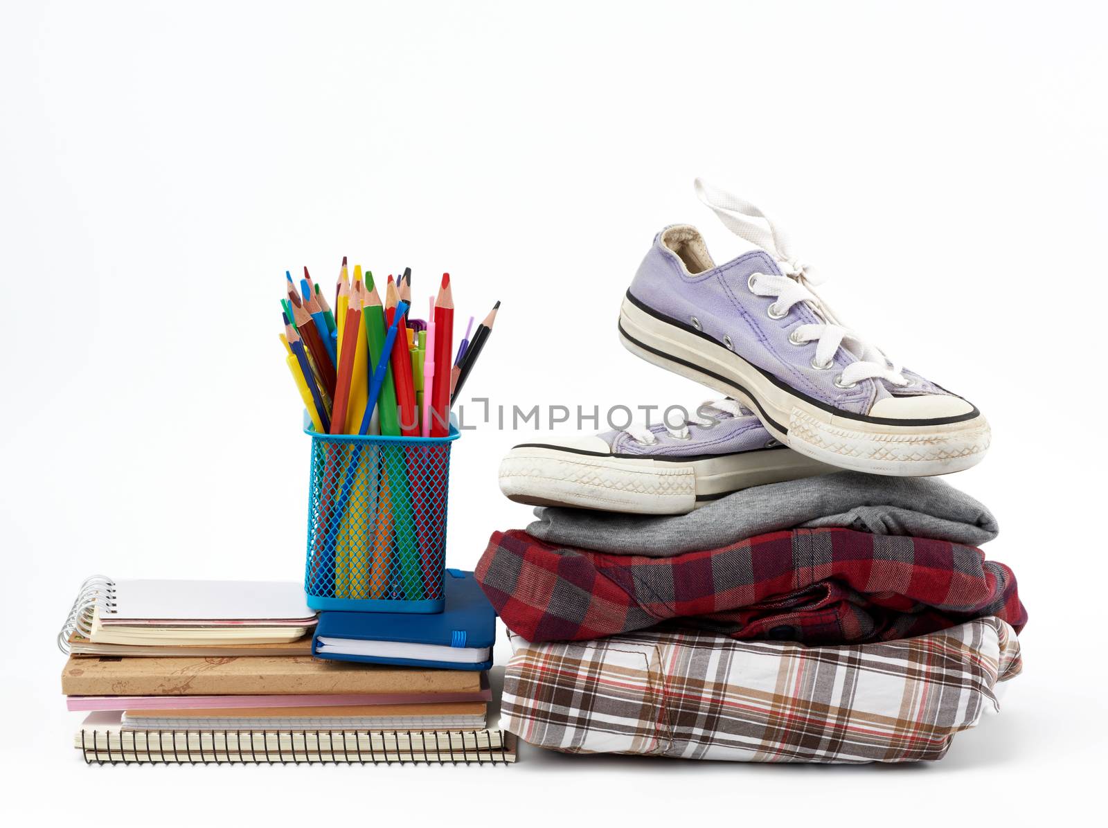 stack of folded clothes, sports sneakers, stationery on a white background, concept for helping the needy, donation