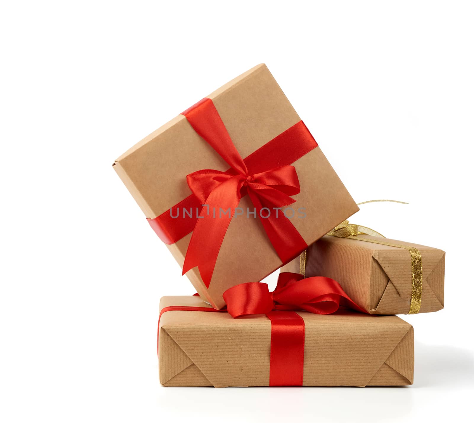 stack of gifts wrapped in brown kraft paper and tied with silk golden and red ribbon, boxes isolated on white background, element for designer
