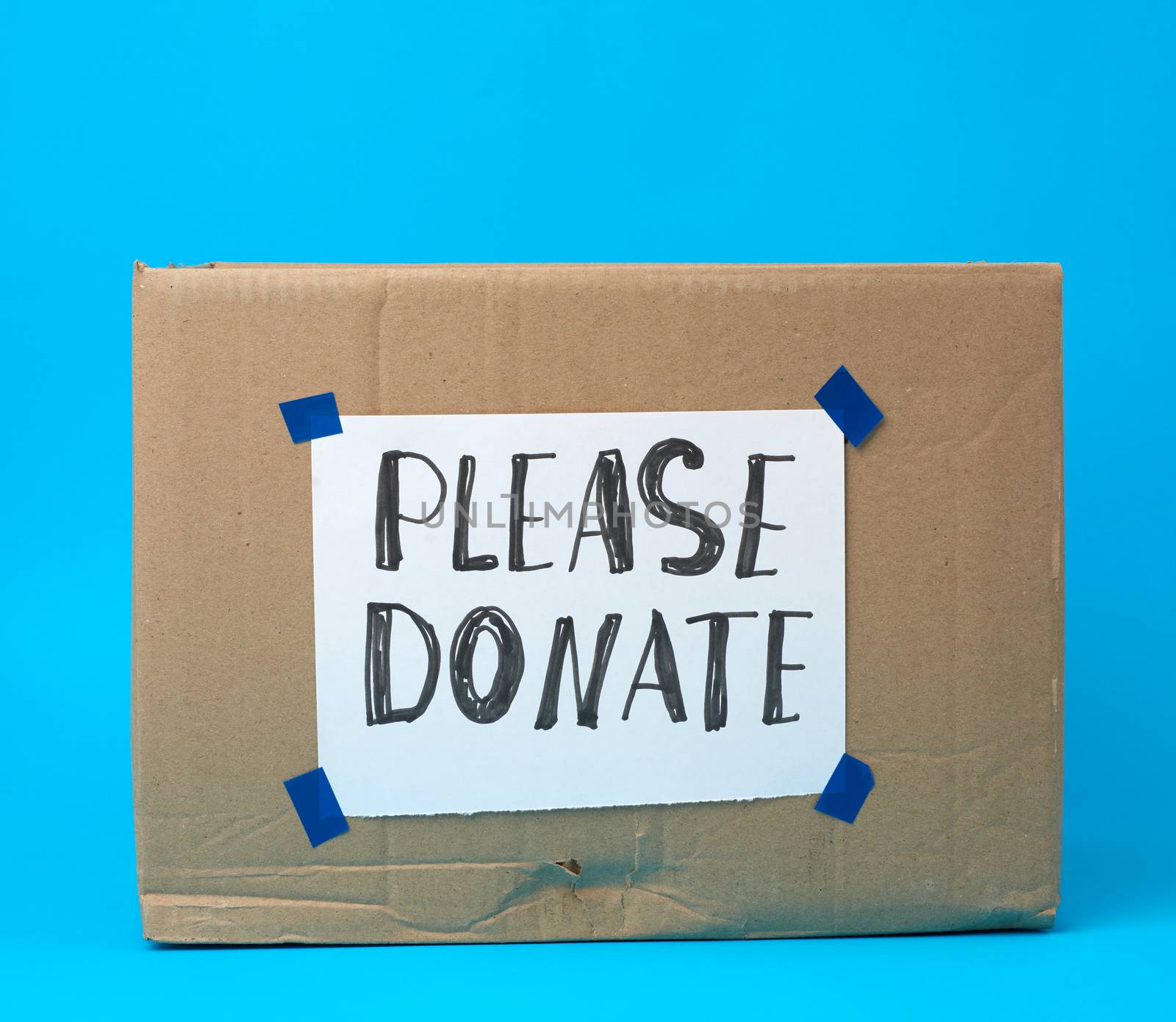 brown cardboard box with a pasted white sheet and the inscription please donate on a blue background, help concept