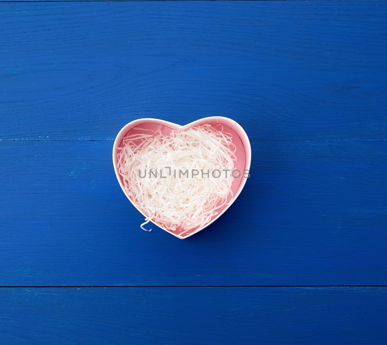 open empty heart-shaped box on a blue wooden background, top view