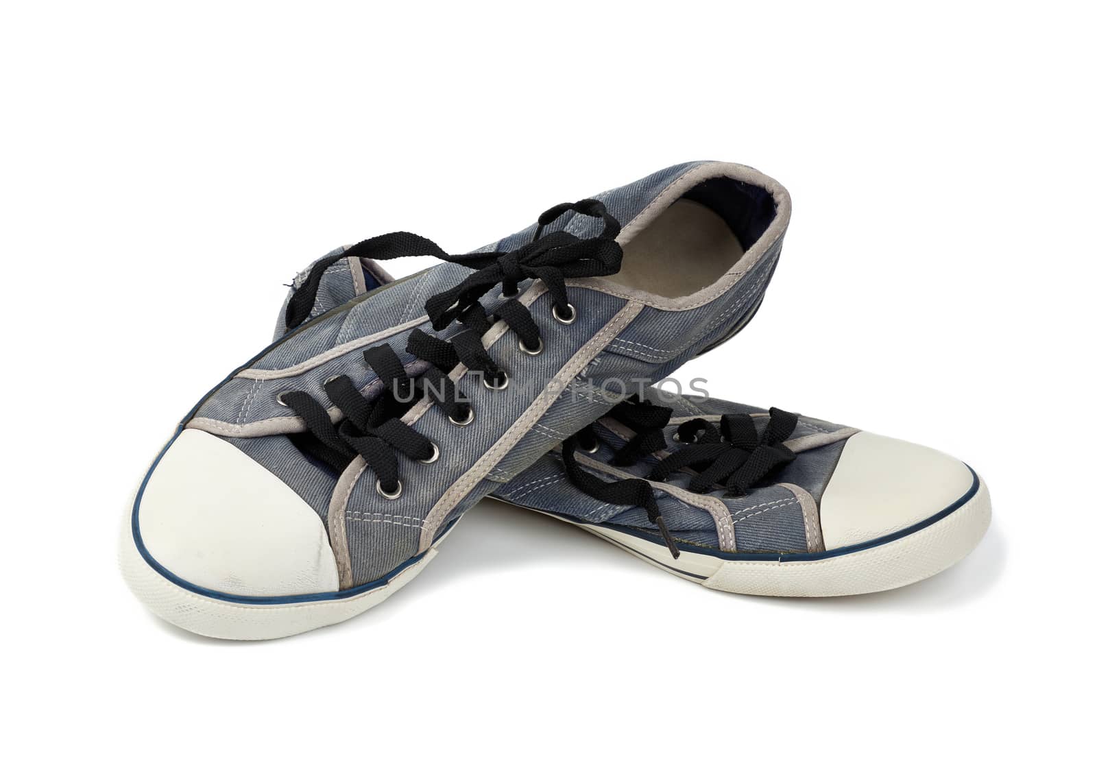 pair of blue worn textile sneakers with black laces isolated on a white background, front view