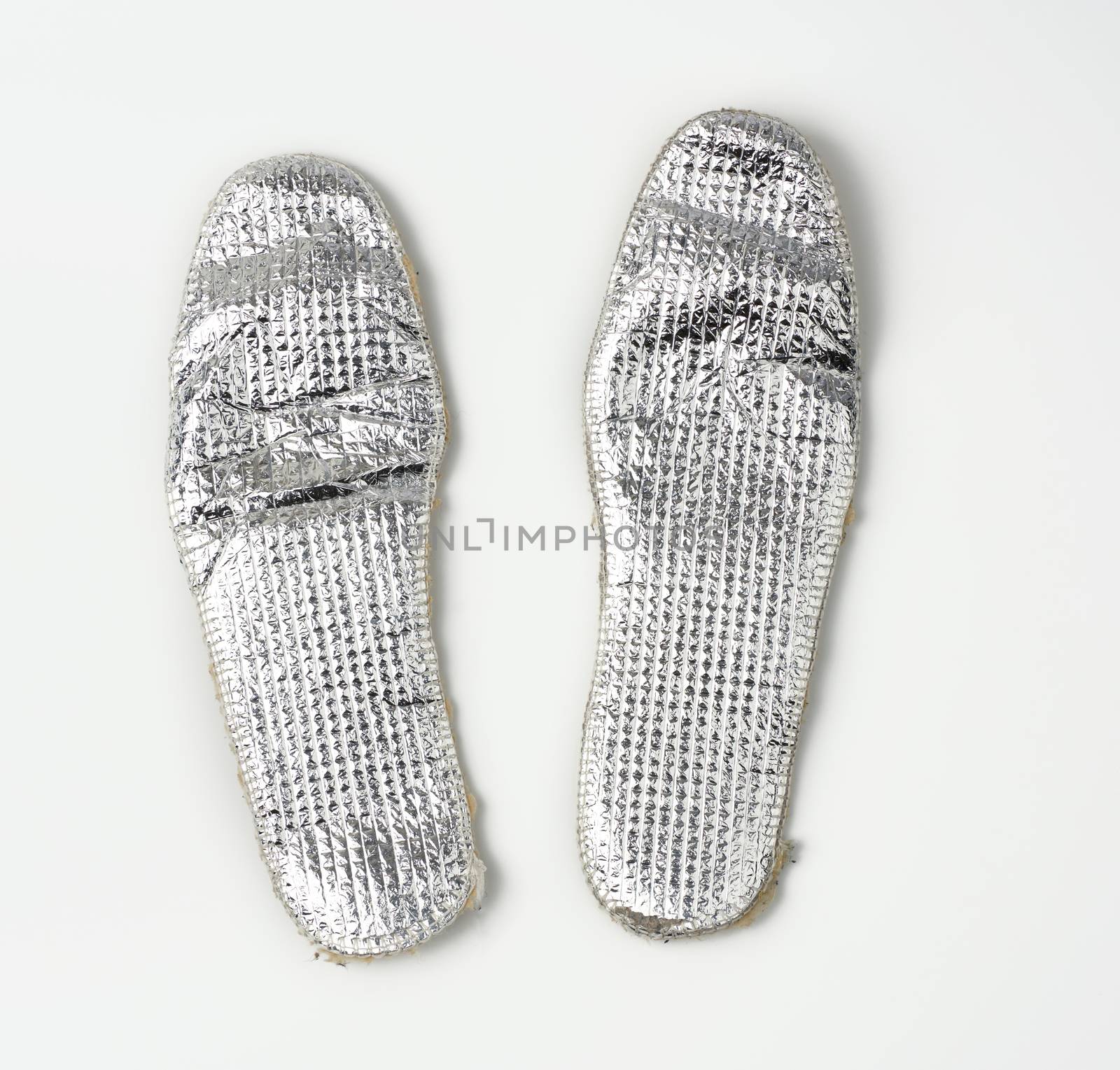 pair of shoe insoles with insulation and foil on a white background, top view