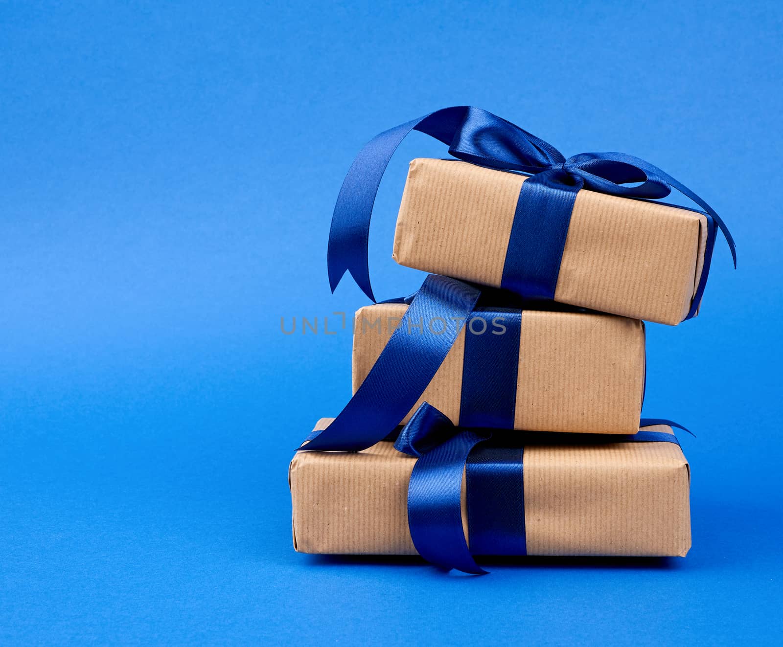 rectangle box wrapped in brown kraft paper and tied with a silk blue ribbon, gift on a dark blue background