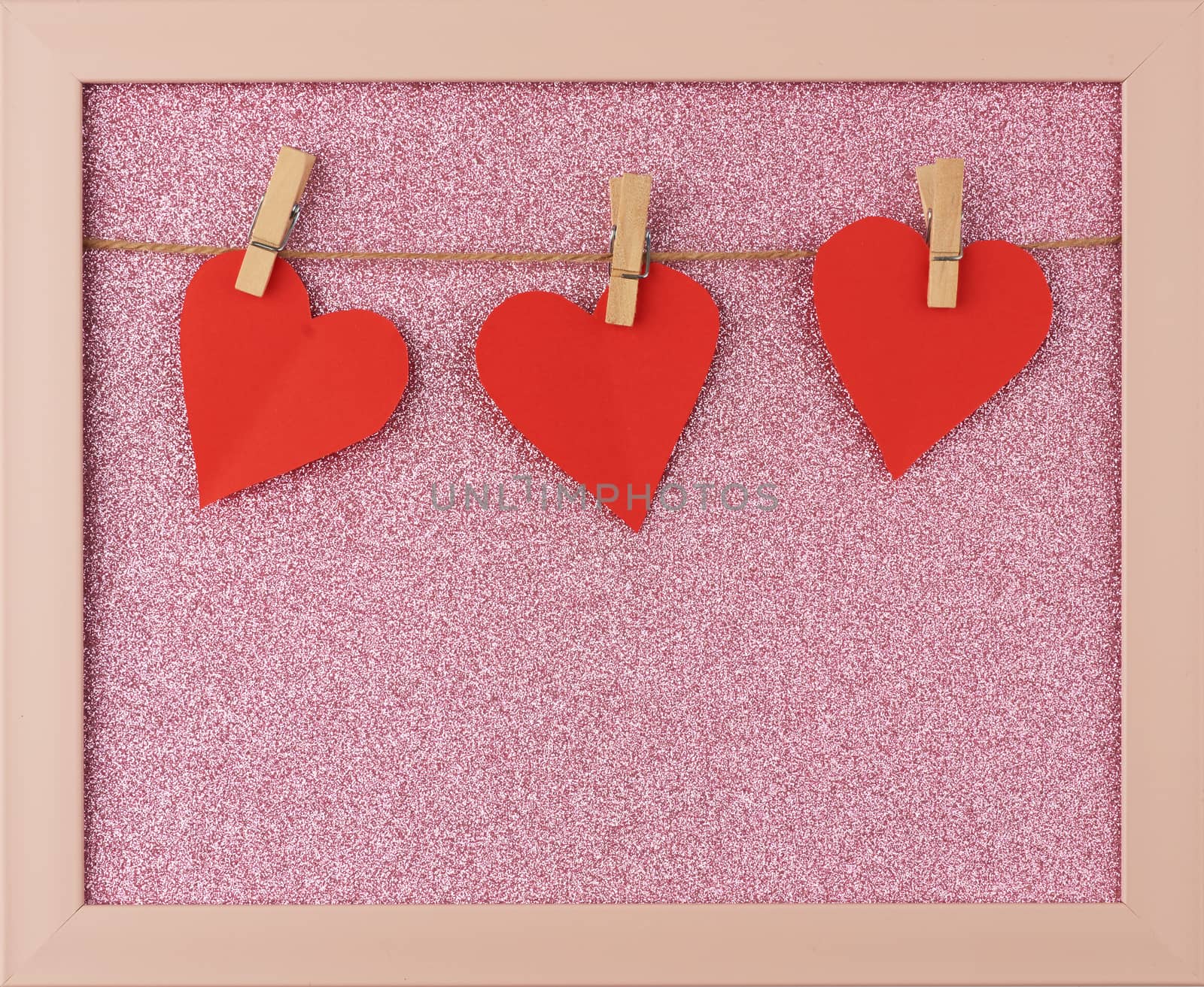 carved red paper hearts hanging on a brown rope, pink shiny background, valentines day card