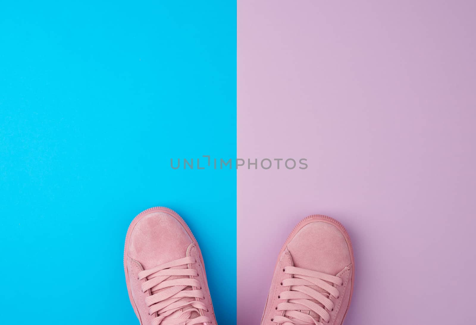 pair of sports pink sneakers with laces on a blue background, top view, place for text 