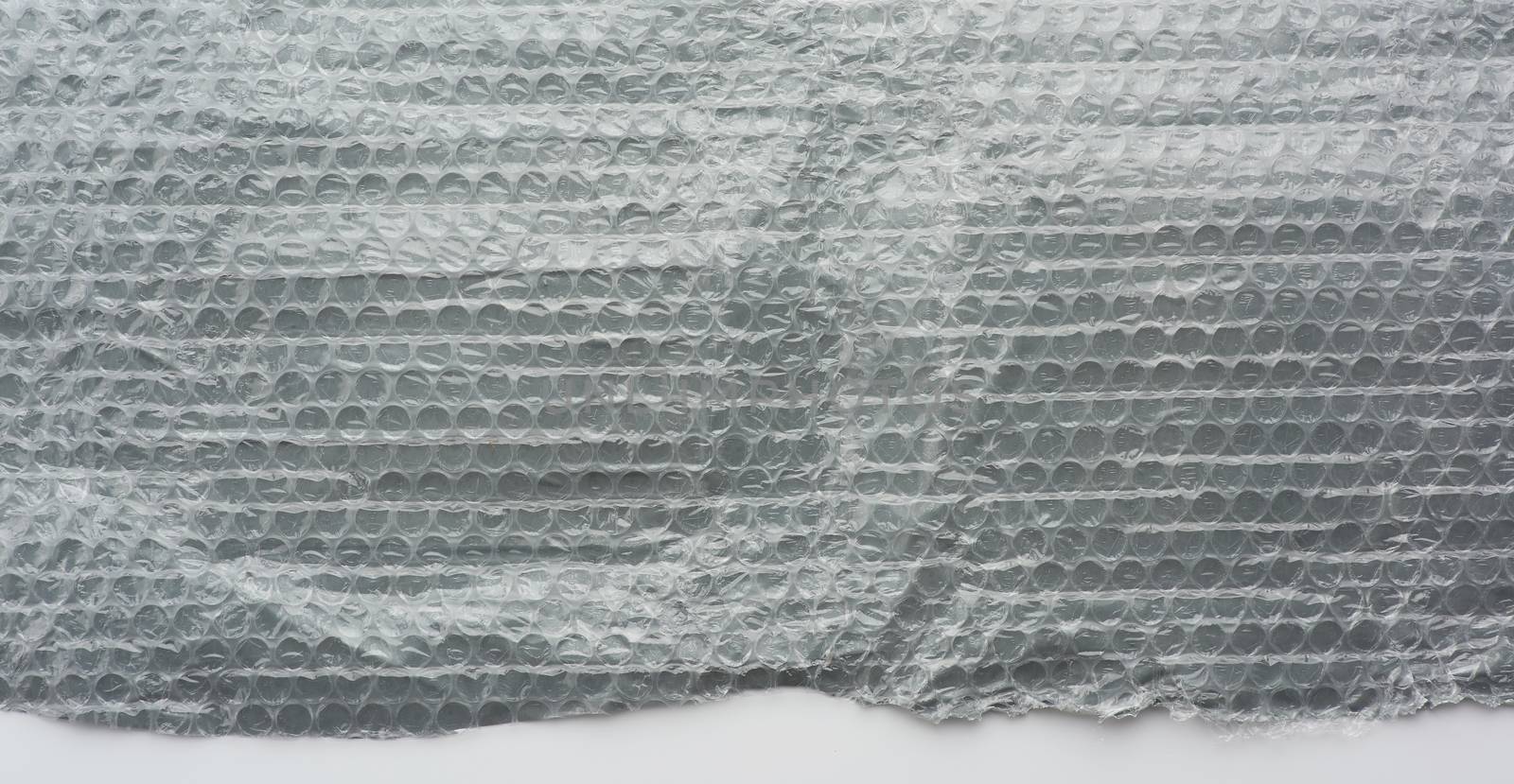fragment of a transparent film with air for the transportation of parcels is glued on gray polyethylene, inside of the envelope