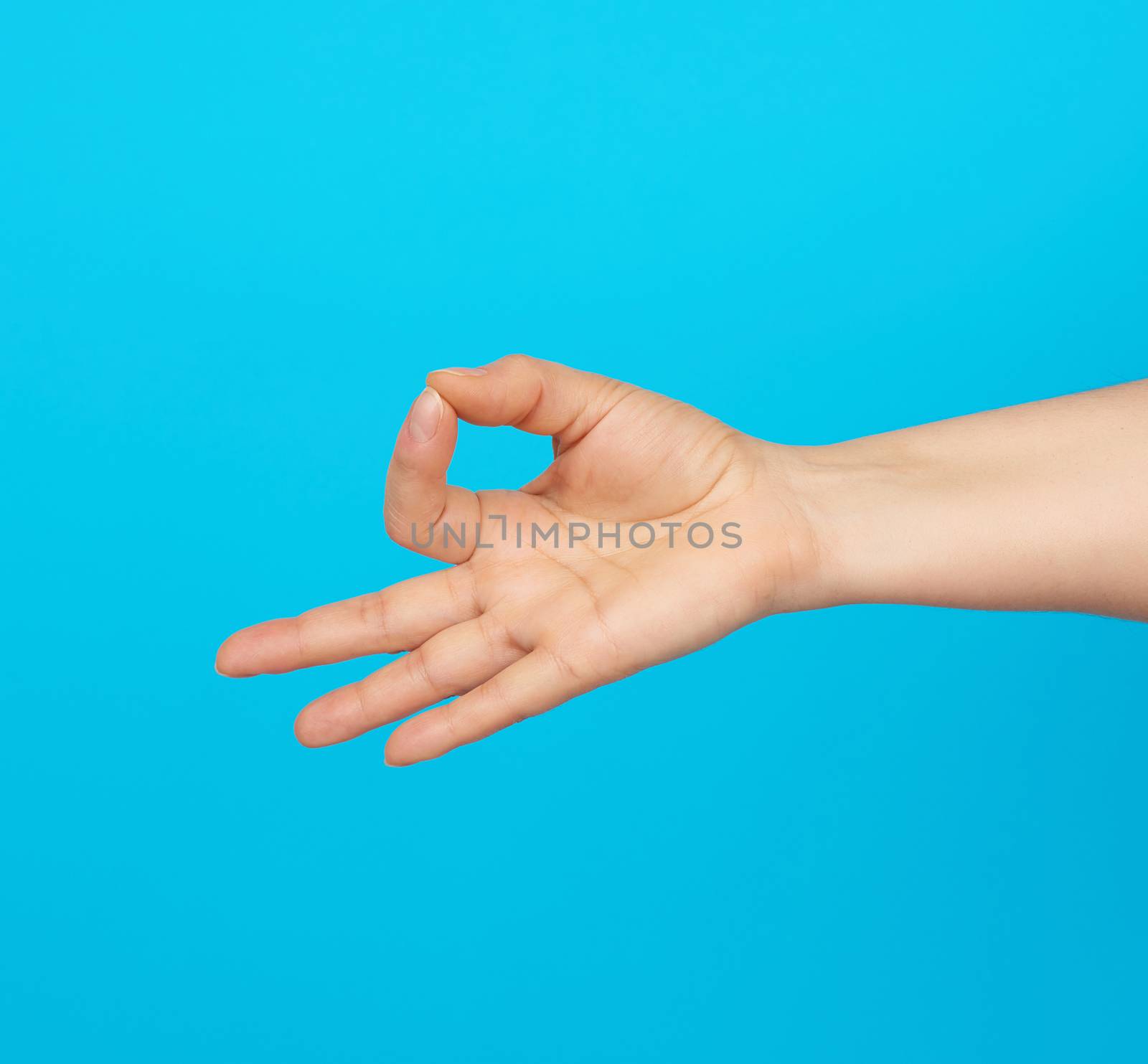 female hand shows the mudra of Knowledge on a blue background, concept of relaxation and meditation