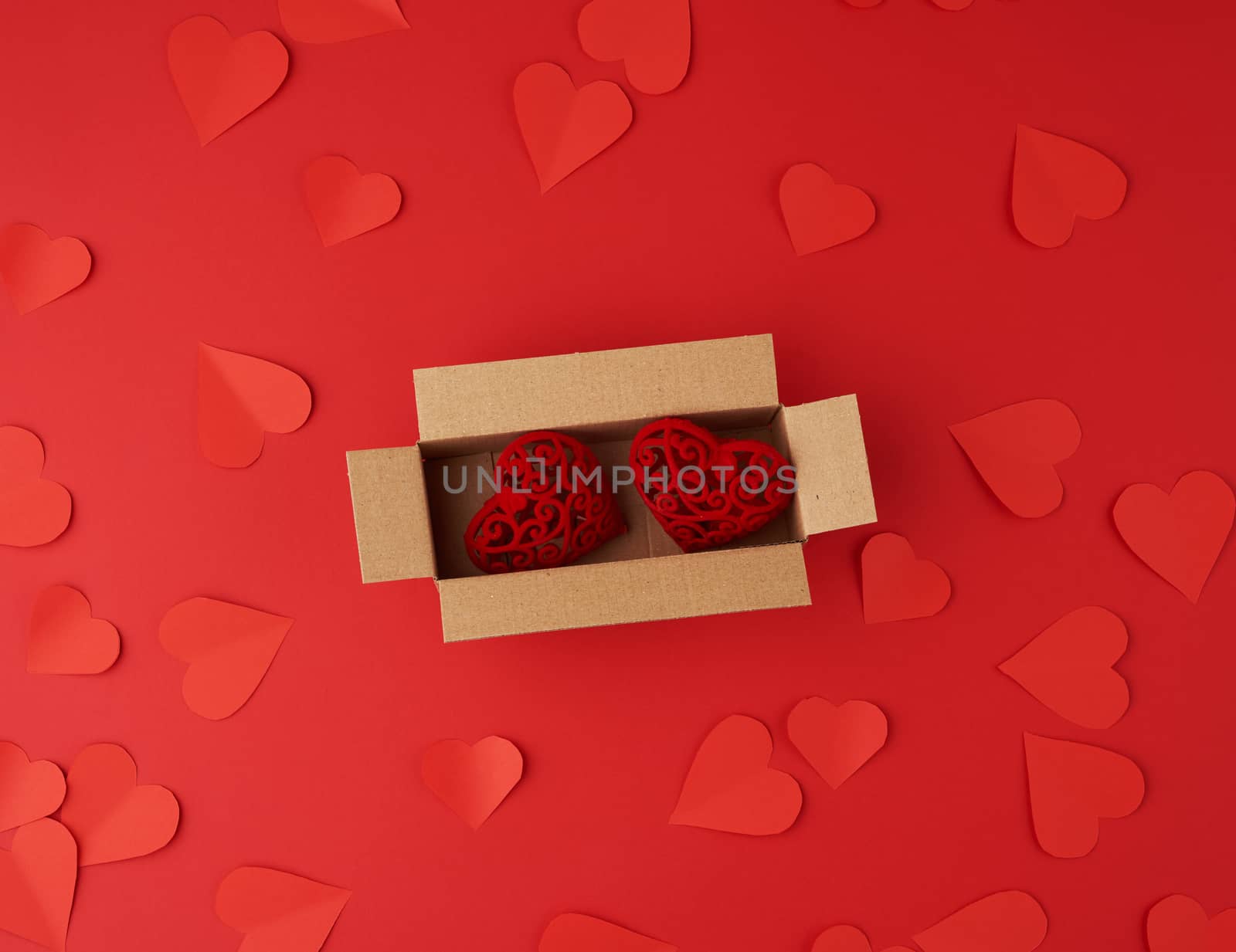 hearts cut out of red paper on a red background, festive backdrop for Valentine's Day, flat lay