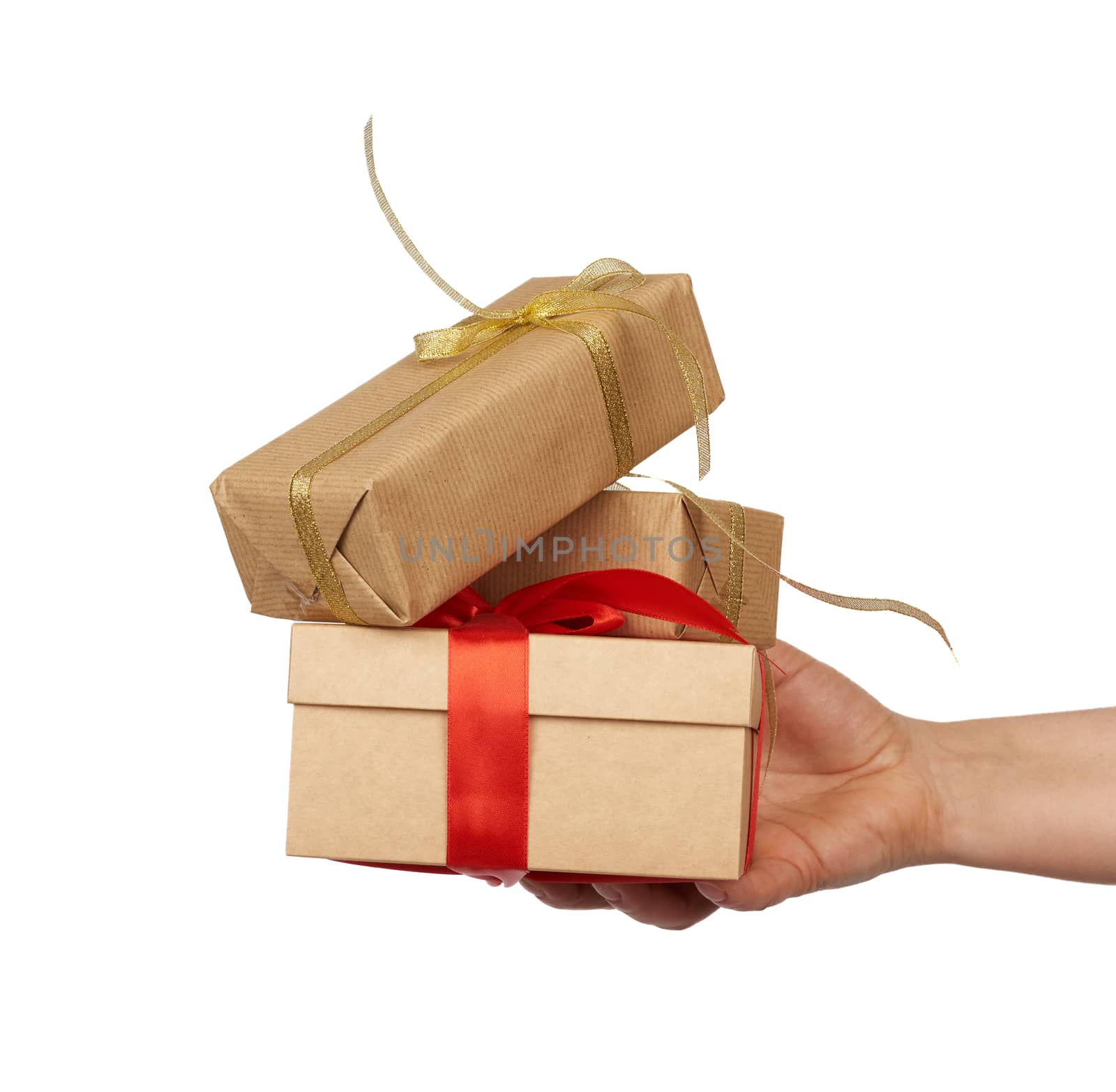 hand holds a stack of wrapped gifts in brown craft paper with tied silk bows, subject is isolated on a white background