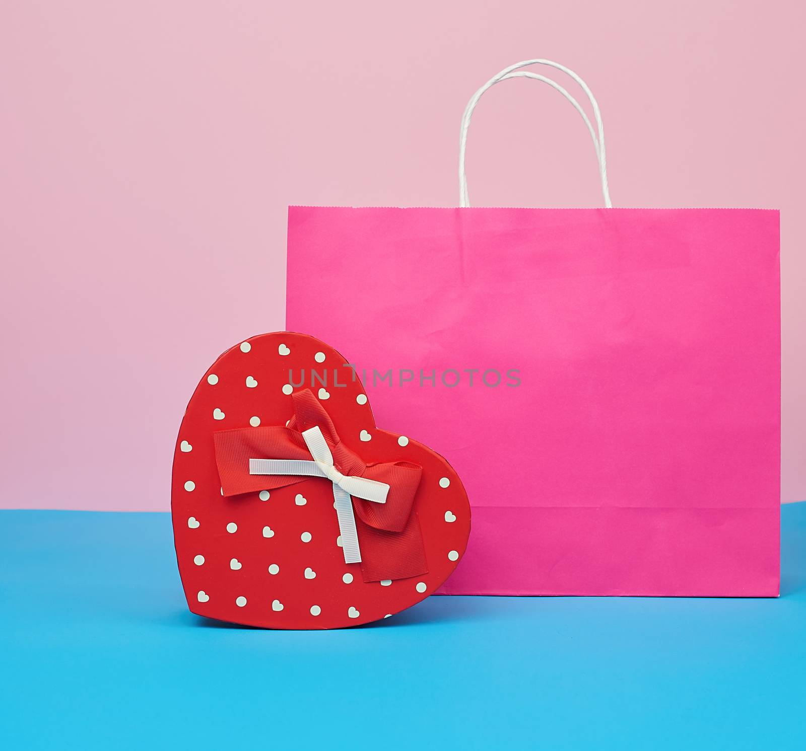 red paper box with a gift and pink paper bag for shopping stand on a pink-blue background